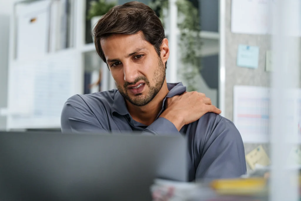 Man at desk holding shoulder